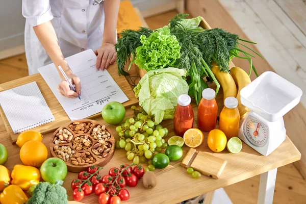 Dietologe schreibt gesunden Ernährungsplan für Patienten mit gesundem Essen auf dem Tisch, Richtiges Ernährungskonzept — Stockfoto