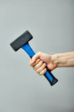 Gri arkaplanda plastik saplı mavi metal çekiç