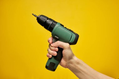 Sarı arkaplan üzerinde izole pilli tornavida veya matkap