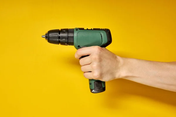 Green cordless battery powered drill on yellow background