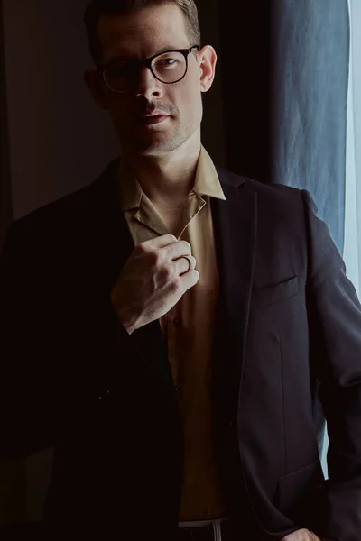 Sötétített portré fiatal fehér férfi elegáns ruhában pózol a kamera — Stock Fotó