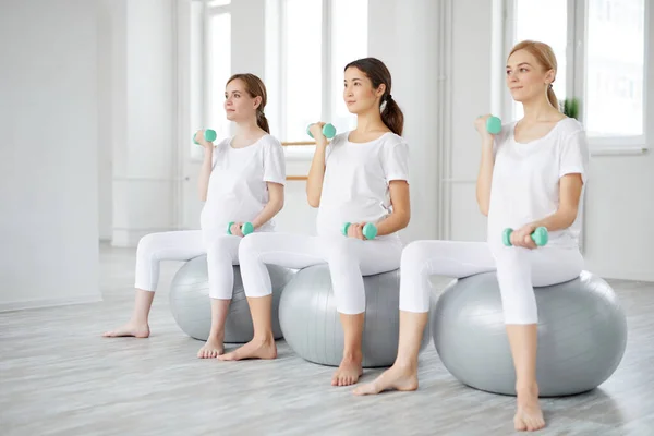 怀孕、运动、健身、人的概念-怀孕妇女在健康球上接受哑铃训练 — 图库照片