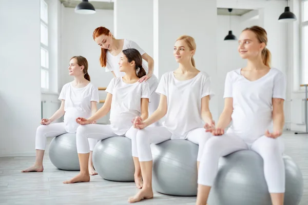 Hamile kadınlar, genç bir kadından doğum öncesi dersleri alıyorlar. Egzersiz yapmaya yardım eden yoga hocası. — Stok fotoğraf