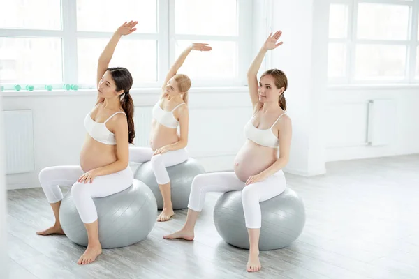Jong vrij zwangere vrouw in sportieve outfit stretching lichaam in studio — Stockfoto