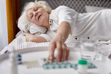 Hasta kişi yatakta yatarken ilaç alıyor.