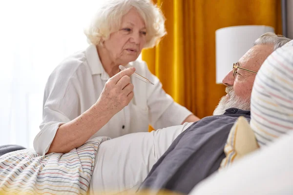 Femme âgée vérifier la température du mari malade à l'aide d'un thermomètre — Photo