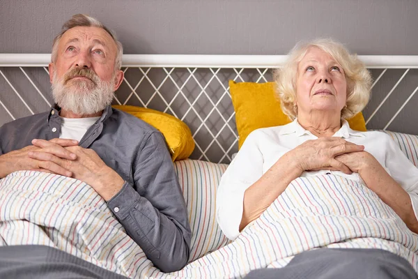 Ledsna pensionerade par ligga på sängen tittar upp, tänker på livet — Stockfoto