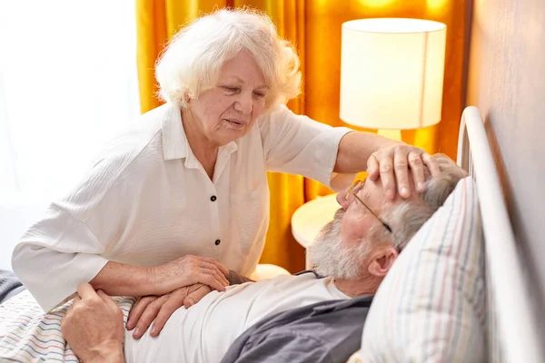 Oudere vrouw is bezorgd over de gezondheidstoestand van zieke man Stockfoto