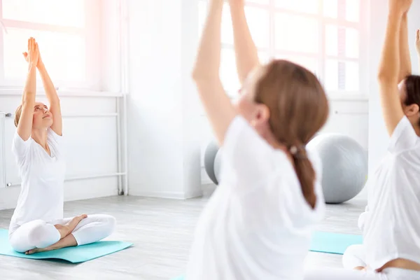 Unga glada gravida kvinnor utövar yoga i lotus pose i studio, med professionell tränare — Stockfoto