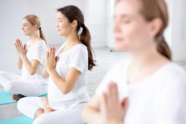 Gruppo di donne incinte felici che esercitano yoga in posa loto in studio, con allenatore professionista — Foto Stock