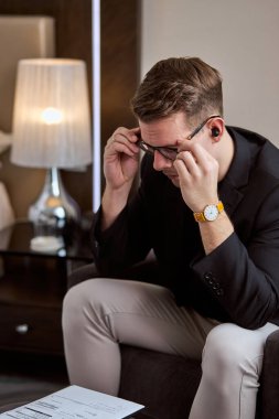 Gergin düşünen düşünceli işadamı işte zor kararlar verir, stresli adam odada yalnız oturur.