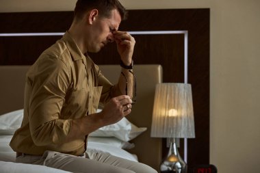 Gergin genç adam baş ağrısı çekiyor, kötü ve depresif hissediyor.