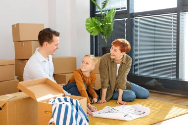 Çocuk sahibi mutlu bir aile ev planlama projesine bakıyor. İç tasarım yerleşiyor, fikirleri yenilemekten bahsediyor.