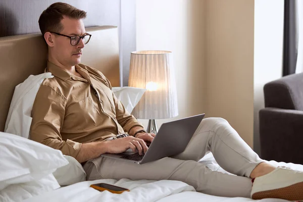 Портрет молодого бизнесмена, работающего на ноутбуке в гостиничном номере, один — стоковое фото