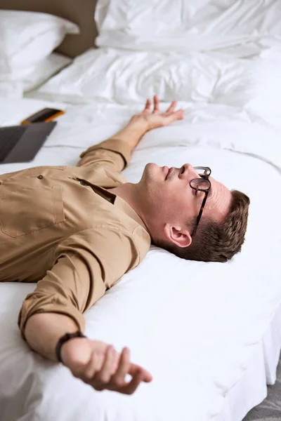 Stanco e oberato di lavoro. Bello caucasico giovane uomo in camicia dormire a letto — Foto Stock