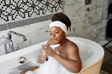 Güzel görünümlü Afrikalı bir kadının banyo yaparken tırnaklarını keserken portresi.