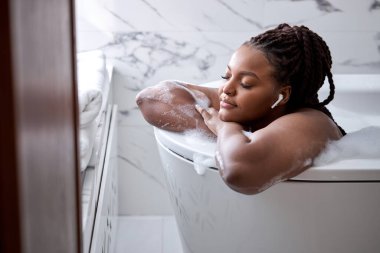 Lüks banyo Afrikalı bir kadın otel spa küvetinde ya da ev banyosunda rahatlamak için dinleniyor.