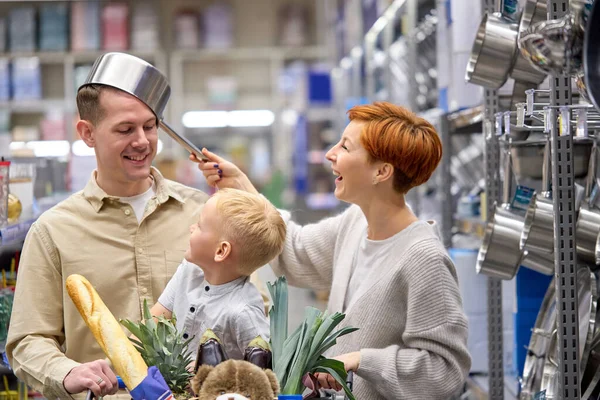 Młoda radosna rodzina radująca się i bawiąca w sklepie — Zdjęcie stockowe