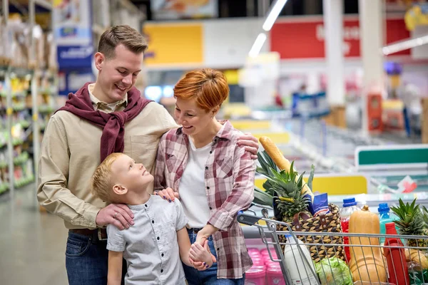 Καυκάσια οικογένεια που αγοράζει υγιεινά προϊόντα διατροφής στο παντοπωλείο, ποζάροντας στην κάμερα — Φωτογραφία Αρχείου