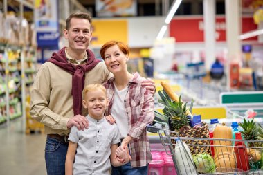 Hoş bir aile marketten sağlıklı gıda ürünleri alıyor ve kameraya poz veriyor.