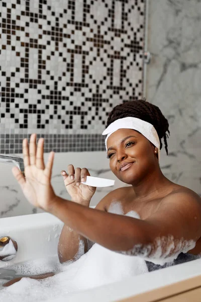 Retrato de la atractiva dama africna sonriente mirando hermosas uñas después de la manicura — Foto de Stock