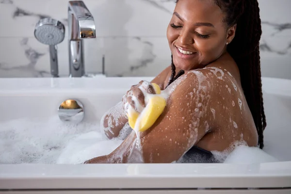 Afro mulher lavando-se, tomando banho em casa usando esponja, espaço livre — Fotografia de Stock