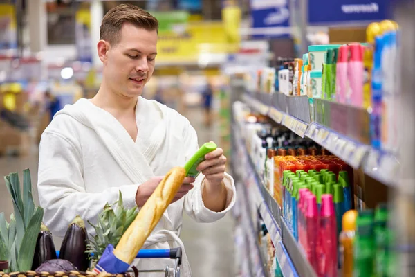 Όμορφος άνθρωπος ψώνια στο σούπερ μάρκετ ανάγνωση των πληροφοριών του προϊόντος, σχετικά με το πλύσιμο σε σκόνη, απορρυπαντικό, σαπούνι, σαμπουάν — Φωτογραφία Αρχείου