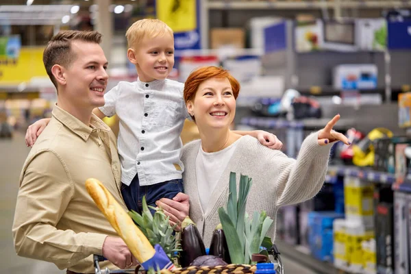 Sorrindo abraço familiar, sorrindo, no amor enquanto faz compras em pé supermercado Em loja corredores dentro de casa — Fotografia de Stock