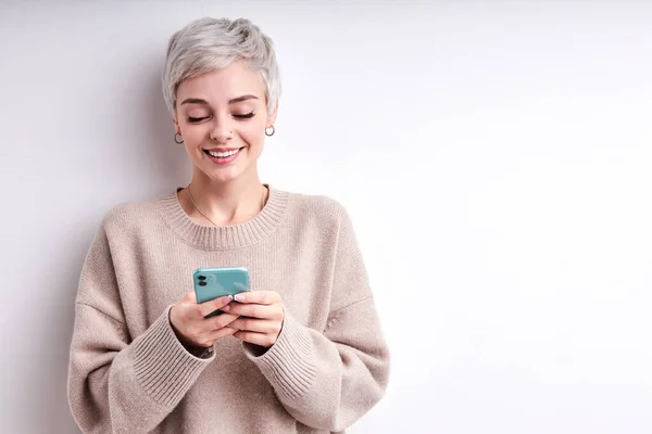 Charmant kort haar vrouw in beige shirt chatten met een vriend met behulp van smartphone — Stockfoto