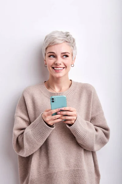 Dromerige vrouw met blond kort haar chatten met iemand op mobiele telefoon, lachen schattig — Stockfoto