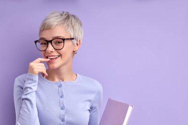 Gözlüklü güzel sarışın kadın elinde defterle çalışmaya hazır.