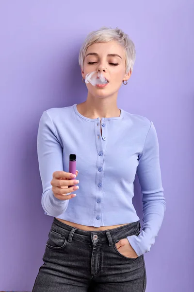 ผู้หญิงผมสั้นที่มีสไตล์สูบบุหรี่ vape แยกกันบนพื้นหลังสีม่วง คอนเซ็ปต์ไอ — ภาพถ่ายสต็อก