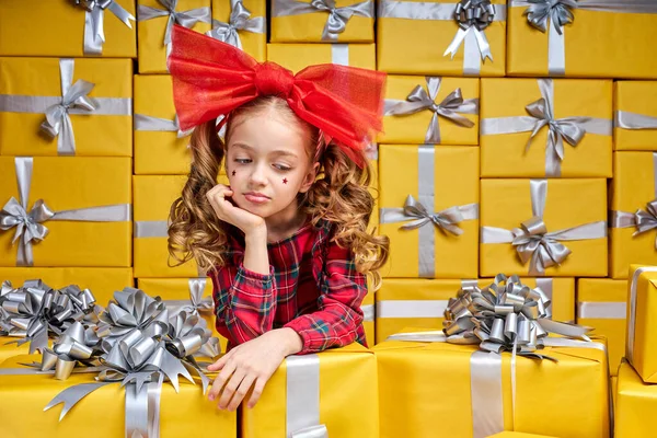 Linda niña molesta por algo posando al lado de pilas de cajas de regalo — Foto de Stock