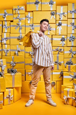 Alışveriş torbaları taşıyan genç Asyalı beyefendi, doğum gününü kutlamaya gidiyor, tebrikler.