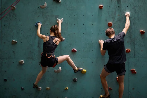 Young couple bouldering on rock climbing wall at indoor gym — Stock Photo, Image