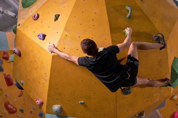 年轻男子登山运动员攀爬人造岩石，过着积极的生活 — 图库照片