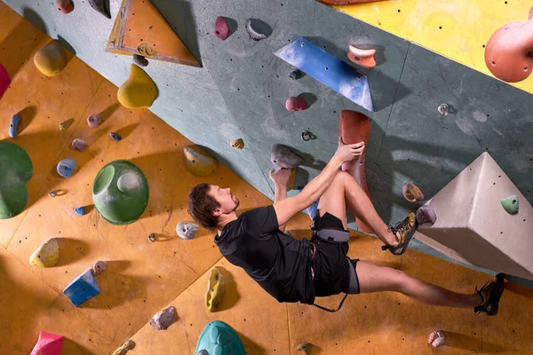 Free climber young man climbing on practical wall indoor, bouldering alone — Stock Photo, Image