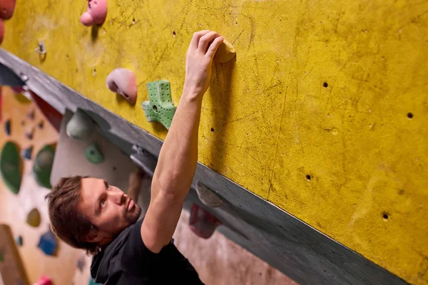 Masculino em sportswear escalada montanha de rocha para aventura e esporte dentro de casa — Fotografia de Stock