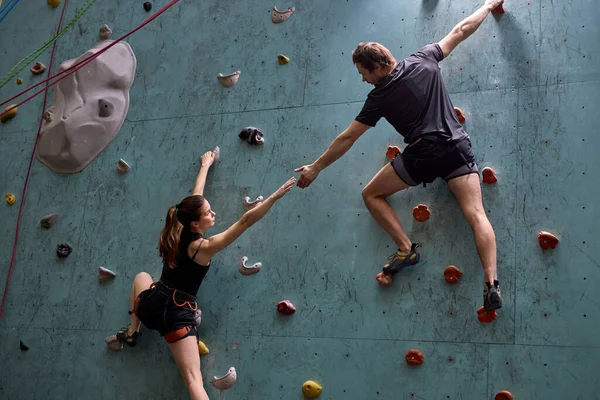 Athletes climbers moving up on steep rock, climbing on artificial wall indoors — Stock Photo, Image