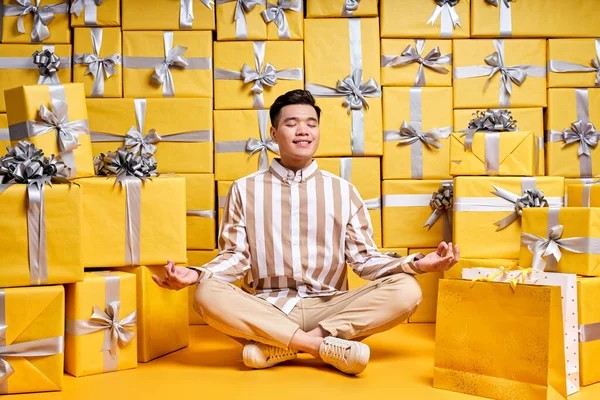 Chico chino sonriente fresco mantener la calma rodeada de cajas de regalo — Foto de Stock