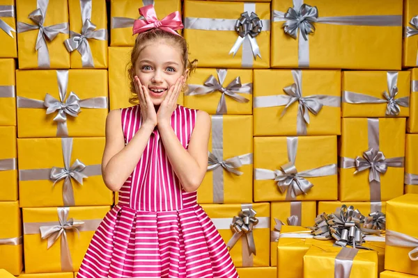 Emocionado niña posando en el estudio rodeado de cajas de regalo celebrando cumpleaños, regocijando muchos regalos — Foto de Stock