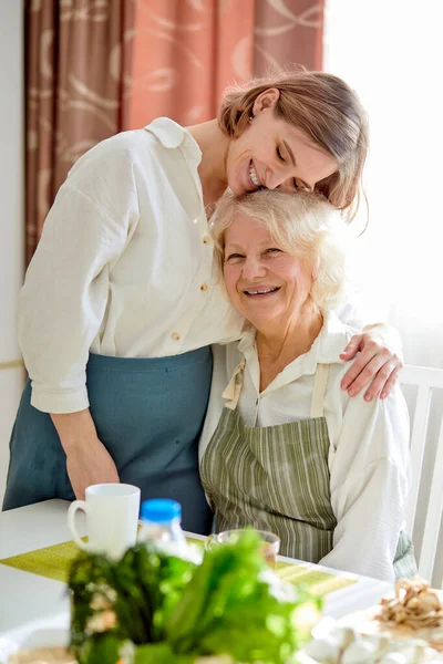Portret van een schattig gezin, oma en jonge vrouw knuffelen, na het koken — Stockfoto