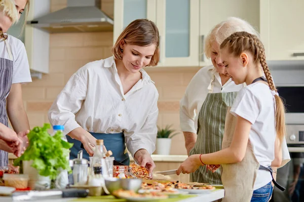 Felnőtt nő ad főtt pizza gyermek lány, a konyhában — Stock Fotó