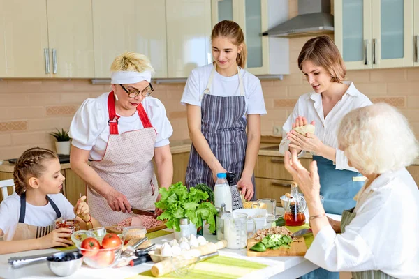 Positive diverse generation family women chopping ingredients for pizza, cooking