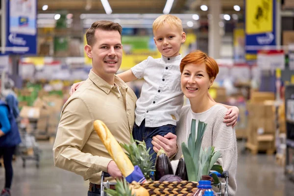Uśmiechnięta rodzina przytula się, uśmiecha, zakochuje podczas zakupów w supermarkecie stojąc w sklepach w pomieszczeniach — Zdjęcie stockowe