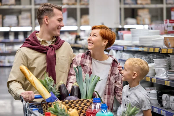 Adorável ruiva mulher e menino olhar para o homem, tendo conversa durante as compras — Fotografia de Stock