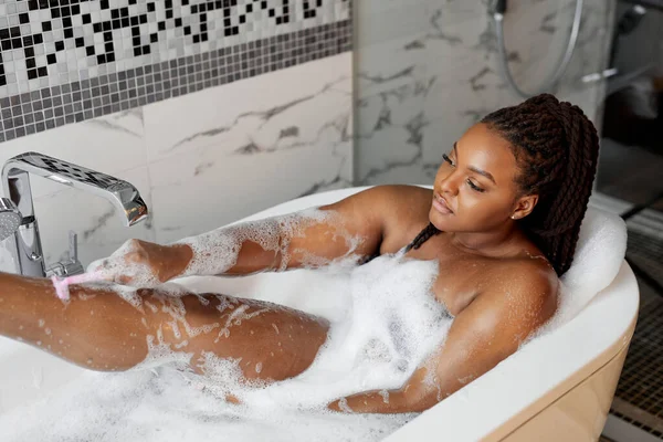 집에서 목욕하면서 섹시 한 다리를 면도 하고 있는 젊은 여성의 모습, 복사 공간 — 스톡 사진