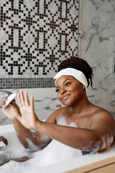 Donna africana seduta sulla vasca da bagno prendersi cura delle unghie, facendo manicure con Nailfile — Foto Stock