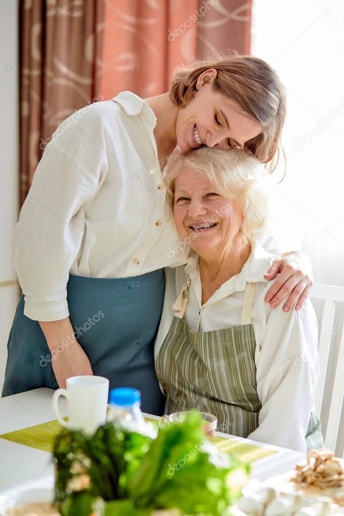 Portrait of cute family, grandma and young woman hugging, after cooking