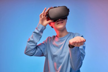 VR gözlüklü genç çocuk kollarını aç ve video oyunu sırasında bir şeyler hayal et.